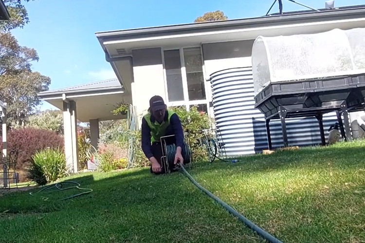 nowra downpipe cleaner is rolling up his hose after a hard days work.

